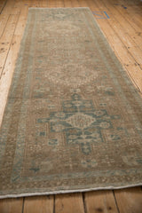 Angled view of a vintage Heriz runner showing its length, distressed texture, and geometric pattern.