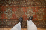 A vintage Heriz runner's distressed texture showing its red and blue geometric medallions.