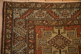 Corner of a Heriz rug with a serrated leaf border and checkered motifs in red, blue, and brown.