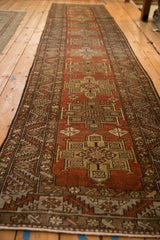 Angled view down the length of a distressed Heriz runner's repeating geometric medallions.