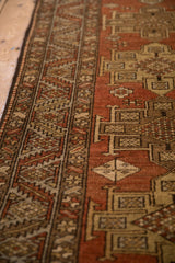 Angled detail of a vintage Heriz runner's serrated leaf border and brick-red low pile.