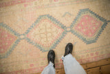Worn, low-pile texture of a vintage Serab runner with pink and sky blue geometric medallions.