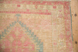 Worn corner of a distressed Serab runner with pink, blue, and ivory geometric floral borders.