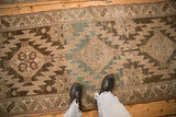 A person's perspective on the distressed texture and geometric patterns of an antique Karabagh runner.