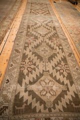 Angled view down the length of a distressed Karabagh runner showing its repeating geometric medallions.