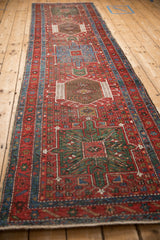 Full length angled view of a vintage Persian Karaja runner with repeating geometric medallions.