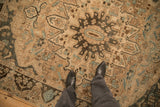 Even wear on the starburst medallion of a distressed Bakhtiari carpet in sand, charcoal, and blue.
