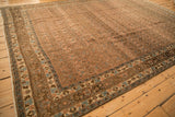 An angled view of a distressed Bijar carpet's multiple borders, showing the turtle samovar motif.