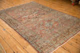 Angled view of a vintage Mahal rug showing its worn texture and scrolling vine pattern.