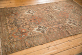 Angled view of a vintage Bakhtiari rug with time-softened tones and a repeating panelled design.