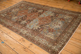 Distressed Malayer rug corner, faded madder red and dusty teal blue diamond pattern.