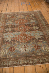 Close-up showing distressed pile of a Malayer rug with teal and rust floral designs.