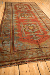 Long perspective view of a vintage Persian runner with a serrated red field and geometric border.