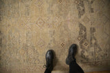 The soft, worn texture and low pile of a distressed Peshawar rug in muted sand, beige, and charcoal hues.