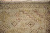 Close-up showing the hand-knotted texture and meandering vine border of a distressed Peshawar rug.