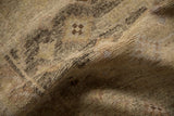 The even wear and low, hand-knotted pile of a distressed Peshawar rug in soft beige and charcoal hues.