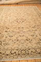 Low angle view across the distressed, sand-colored field of a vintage Persian Arak carpet.