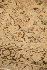 Close-up on the distressed texture of a vintage Arak carpet, showing mostly even wear and floral motifs.