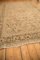 Low angle on a distressed vintage Arak carpet, showing the worn texture and dark floral border.
