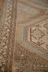 Low pile texture on the geometric borders of a distressed Malayer rug in sand, sky blue, and charcoal.