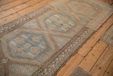 Repeating hexagonal medallions in sky blue and sand along the length of a distressed Persian runner.