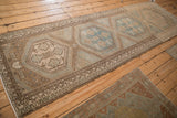 Angled view of a Malayer runner with distressed geometric medallions in blue and sand.