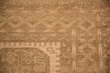 Geometric diamond border detail on a distressed Ersari carpet with a low, evenly worn pile.