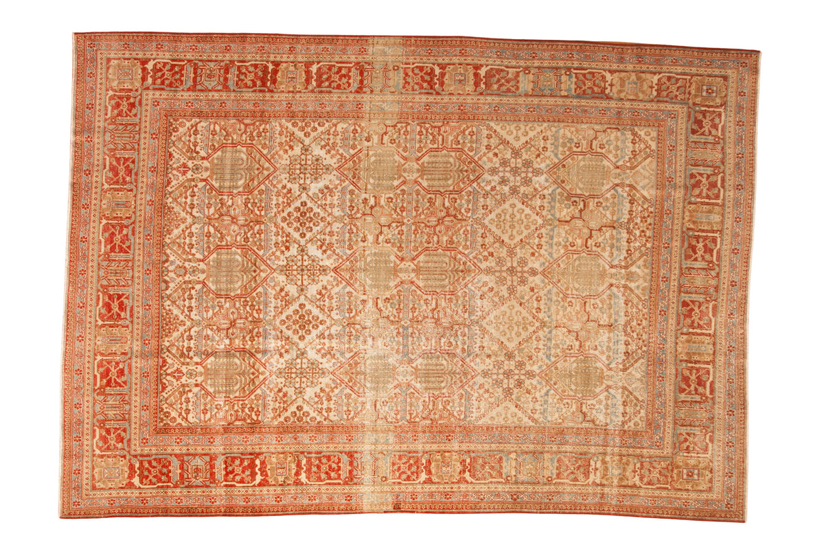 Vintage distressed Joshegan carpet with a diamond floral pattern in pomegranate red, ivory, and sky blue.