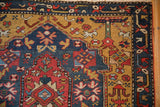 Close-up of the meandering vine border in sapphire blue next to the gold field of the antique Karabagh rug.