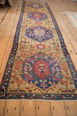 Angled view down the antique Karabagh runner, showing the row of shield-like medallions on gold.