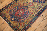 Antique Karabagh runner's meandering vine border beside a shaded gold field with geometric blossoms.