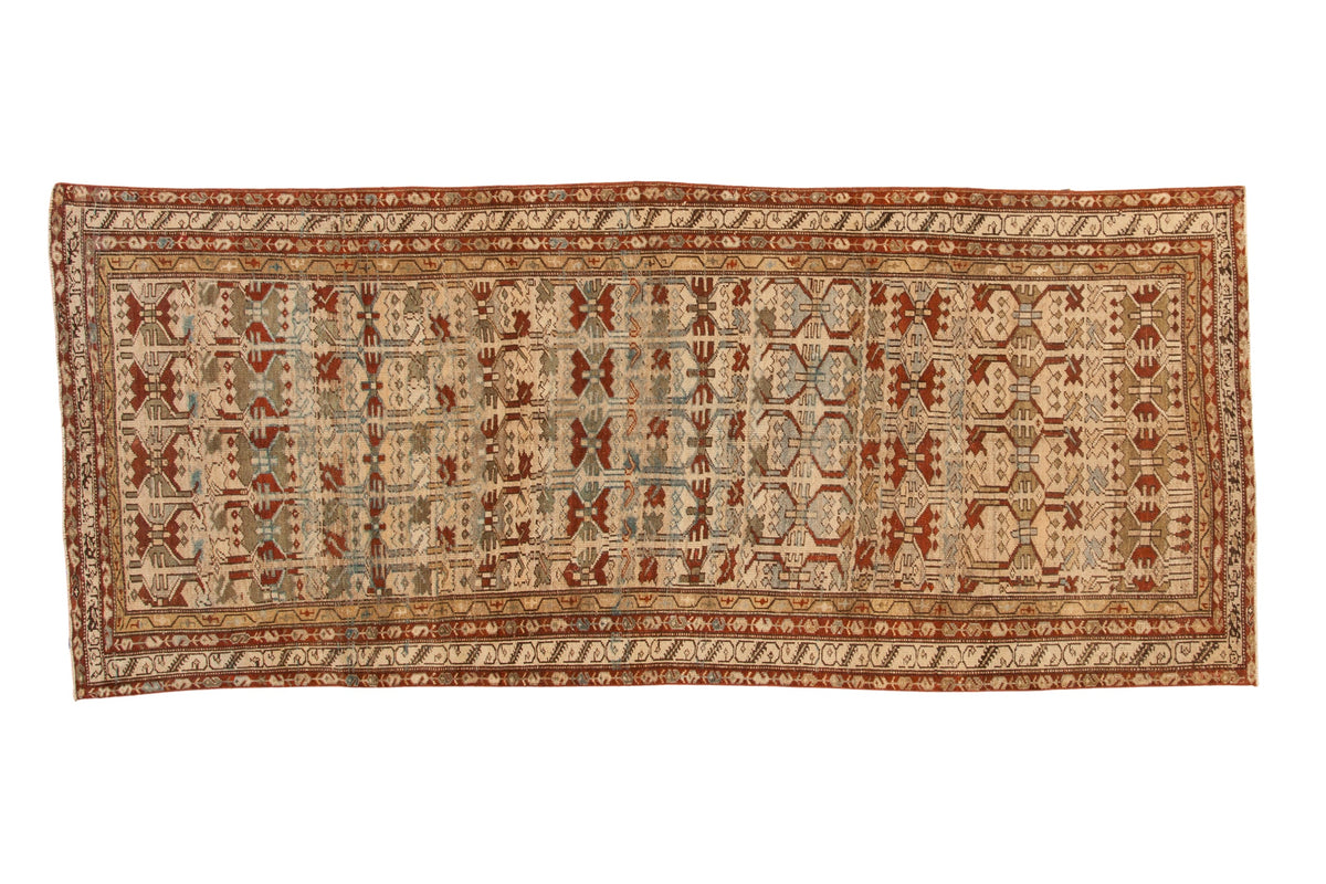 Antique distressed Borchalou rug runner with geometric floral blossoms in sand, burgundy red, and teal.
