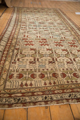 Low angle on an antique Borchalou runner detailing its low pile and repeating geometric floral pattern.