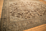 Angled shot of a distressed Kaboutrahang carpet's low-pile texture and chocolate brown floral design.