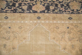 Detail of mostly even wear across the sand-colored field and cobalt border of a vintage Oushak.