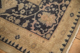 Corner detail of a distressed Oushak rug showing the stylized cartouche border and low, worn pile.