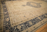 Angled view of a vintage Oushak rug's worn texture, cobalt blue border, and open sand field.