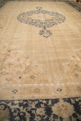 Low-angle view of a distressed Oushak carpet showing the worn texture and cobalt blue medallion on a sand field.
