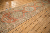 Angled view showing the repeating hexagonal medallions along the length of a distressed Persian runner.