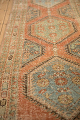 Angled view of a vintage runner showing the worn pile across its hexagonal medallions and border.