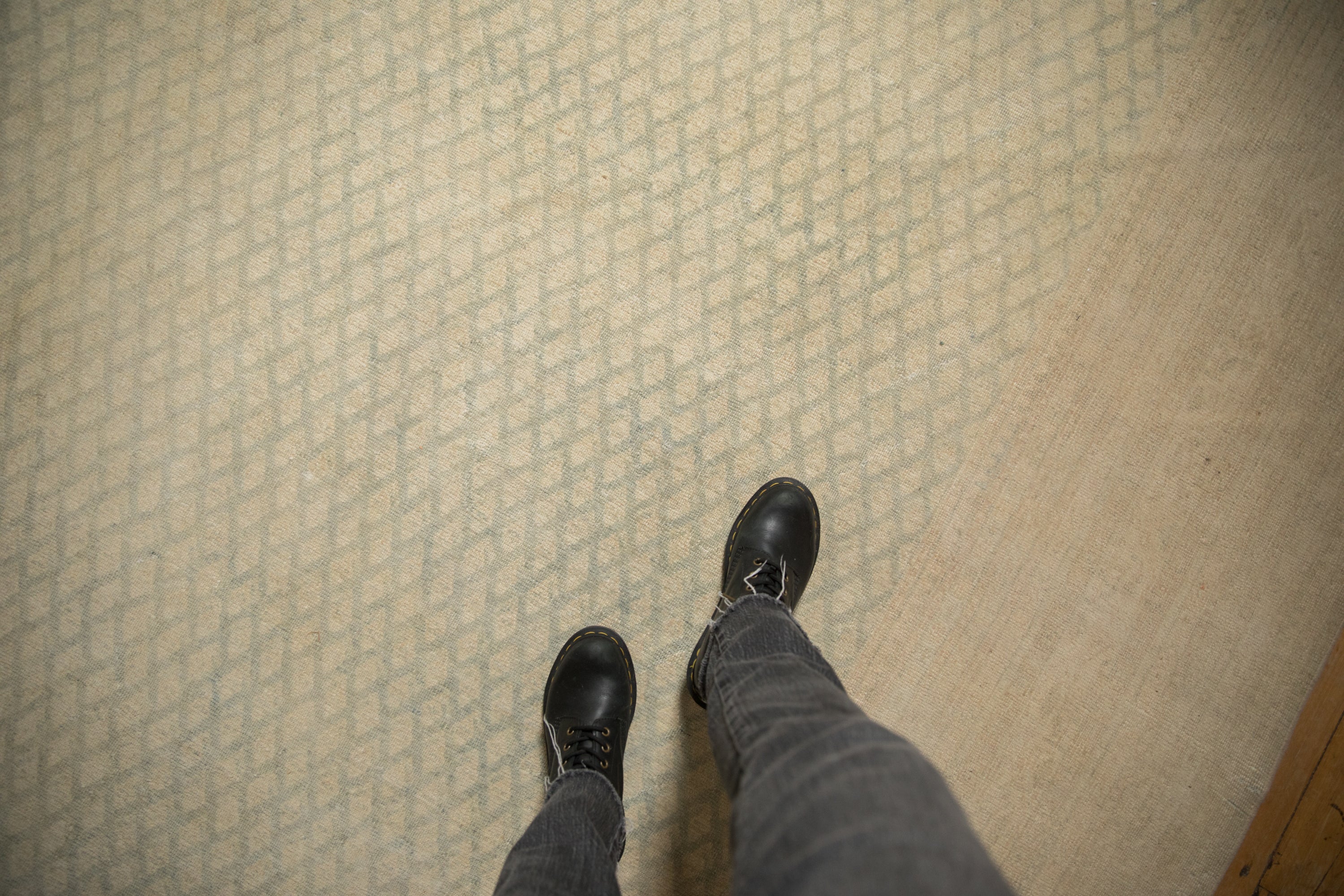 Close-up of the distressed, low-pile texture and faded slate boteh pattern on a vintage Sarouk carpet.