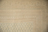 Close-up of the distressed, low-pile texture and faint border motif in ivory and silver.
