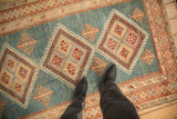 A perspective view down the length of a distressed Malayer rug showing its geometric pattern.