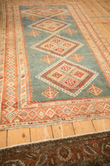 Angled view of a vintage Malayer rug showing the abrashed blue field and column of diamond medallions.
