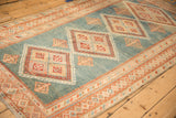 Long angled view of a distressed Malayer rug with red geometric motifs on a varied blue field.