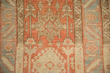 Detail of a Karaja stylized medallion and serrate leaf border on a distressed Persian Heriz rug.