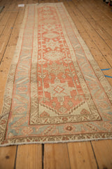 Long perspective of a distressed Heriz runner's Karaja medallions in terracotta and blue.