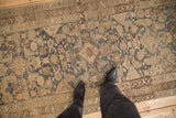 On-floor view of the vintage Persian runner's worn texture and intricate Herati design.