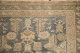 Corner view of the distressed Malayer rug's starburst border and evenly worn, low-pile texture.
