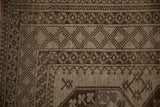 Charcoal and silver pawn and diamond motifs in the distressed geometric border of an Ersari carpet.